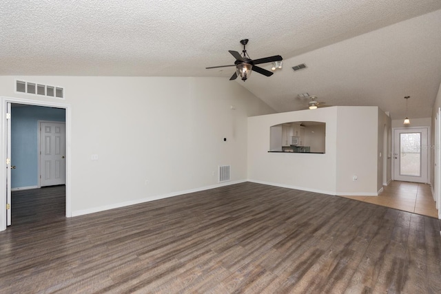 unfurnished living room with dark wood-type flooring, ceiling fan, vaulted ceiling, and a textured ceiling