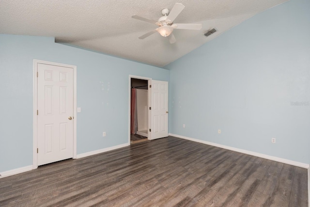 unfurnished bedroom featuring lofted ceiling, dark hardwood / wood-style flooring, and a textured ceiling