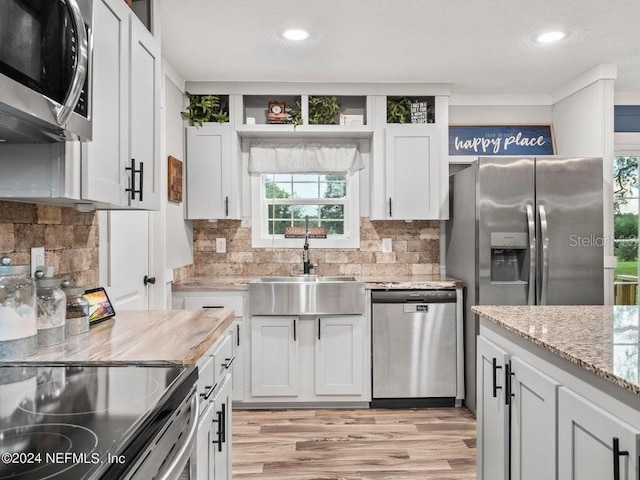 kitchen featuring sink, light stone counters, appliances with stainless steel finishes, decorative backsplash, and white cabinets