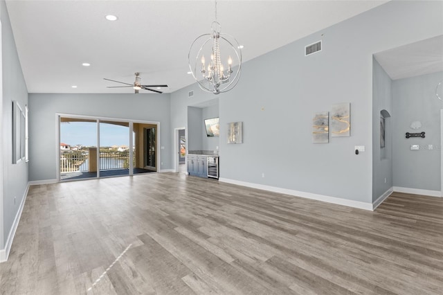 unfurnished living room featuring ceiling fan with notable chandelier, lofted ceiling, beverage cooler, and light hardwood / wood-style floors