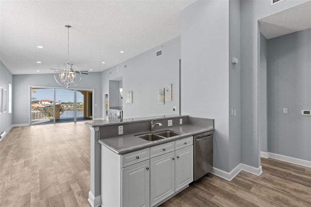 kitchen featuring sink, white cabinetry, an inviting chandelier, stainless steel dishwasher, and hardwood / wood-style floors