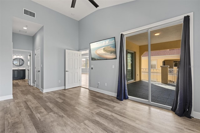 empty room featuring light hardwood / wood-style flooring, high vaulted ceiling, and ceiling fan