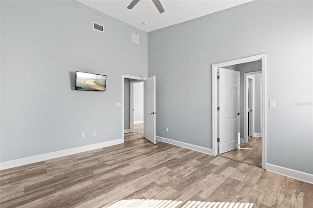 unfurnished bedroom featuring a high ceiling, ceiling fan, and light wood-type flooring