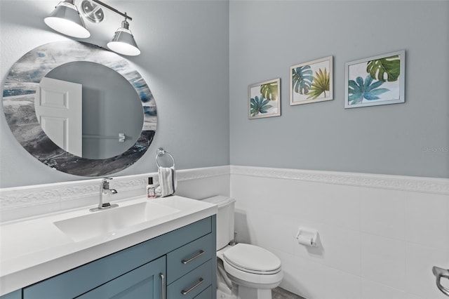 bathroom with vanity, toilet, and tile walls