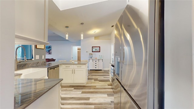 kitchen with appliances with stainless steel finishes, decorative light fixtures, white cabinetry, sink, and kitchen peninsula