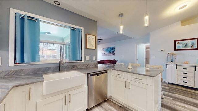 kitchen with decorative light fixtures, kitchen peninsula, dishwasher, light hardwood / wood-style floors, and white cabinets