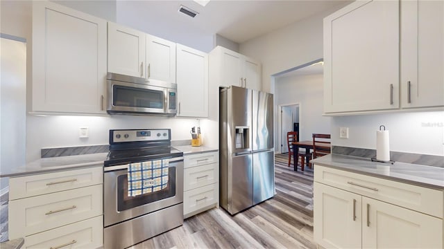 kitchen featuring appliances with stainless steel finishes, light hardwood / wood-style floors, and white cabinets