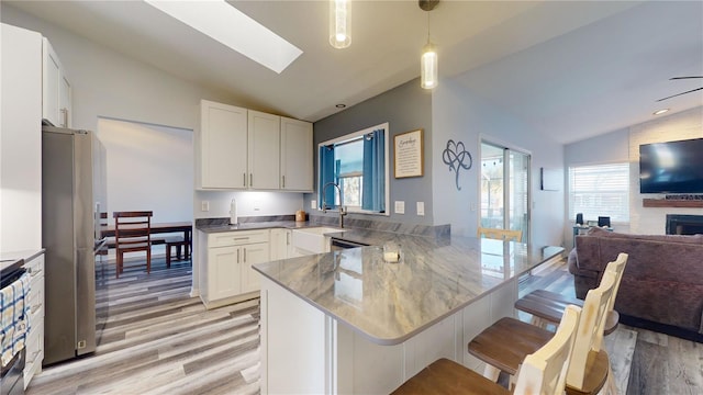 kitchen featuring hanging light fixtures, white cabinetry, a breakfast bar area, and kitchen peninsula