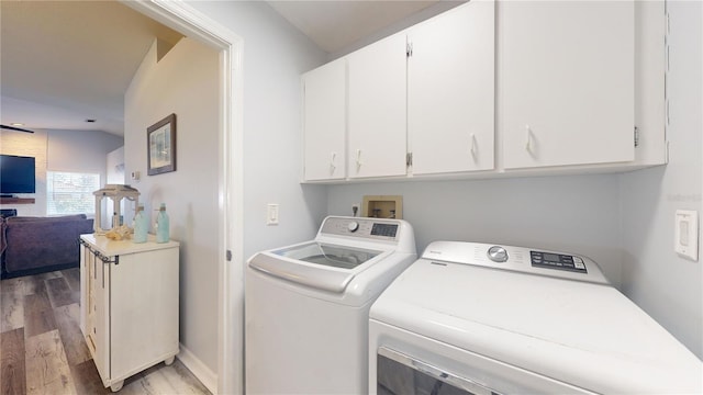 washroom with hardwood / wood-style flooring, cabinets, and washer and clothes dryer