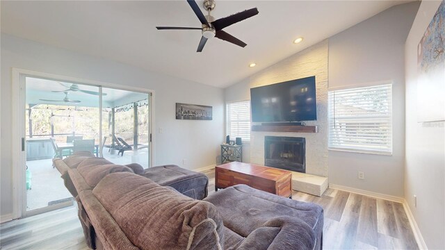 living room featuring light wood-type flooring, ceiling fan, vaulted ceiling, and a wealth of natural light