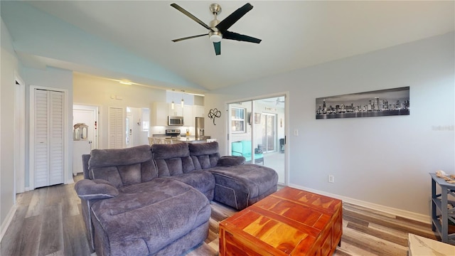 living room featuring hardwood / wood-style flooring, vaulted ceiling, and ceiling fan