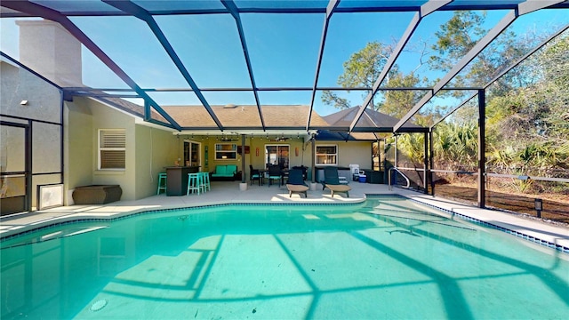 view of swimming pool featuring a patio area, an outdoor bar, and glass enclosure