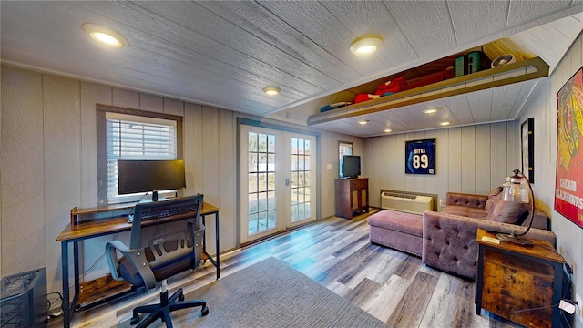 living room featuring wood-type flooring, a wall unit AC, french doors, and vaulted ceiling