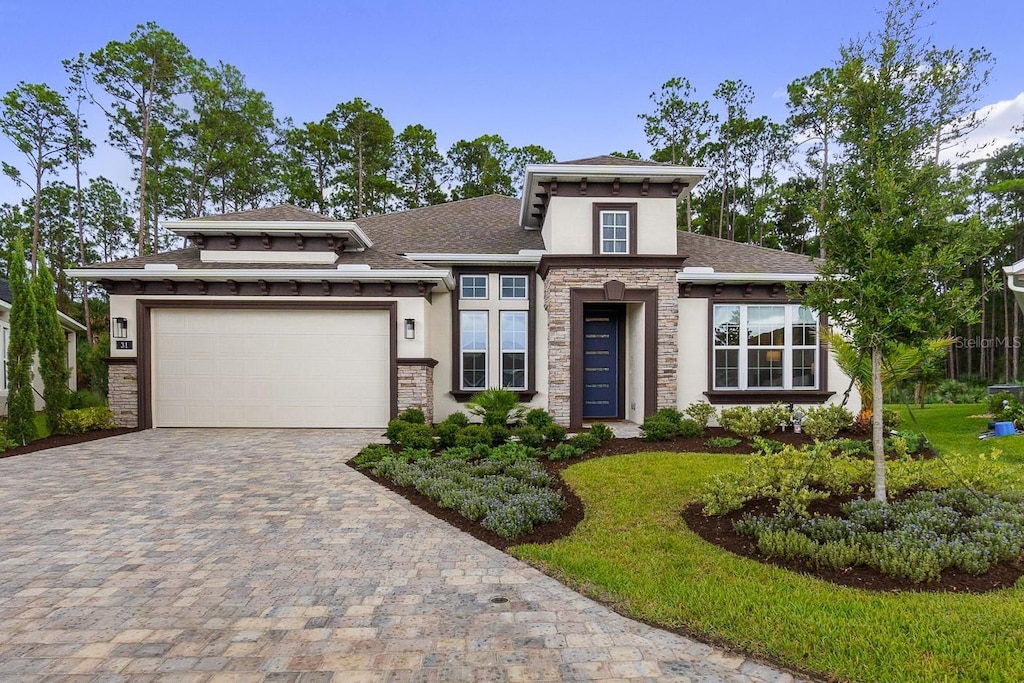 prairie-style house featuring a garage and a front lawn