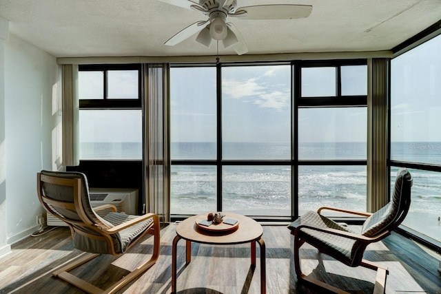 sunroom / solarium with a water view, ceiling fan, and a healthy amount of sunlight