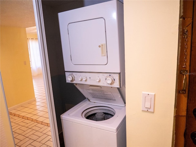 washroom featuring stacked washer / dryer, laundry area, tile patterned flooring, and baseboards