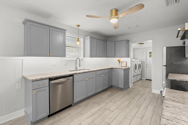 kitchen with sink, appliances with stainless steel finishes, gray cabinetry, hanging light fixtures, and washing machine and clothes dryer