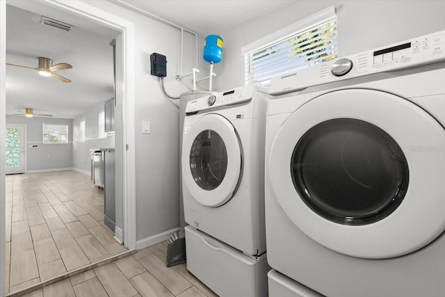 laundry area with ceiling fan, washing machine and dryer, and a healthy amount of sunlight