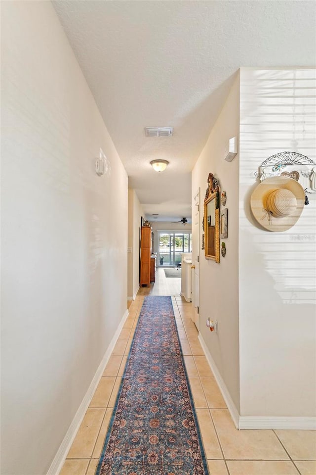 hall with light tile patterned flooring and a textured ceiling