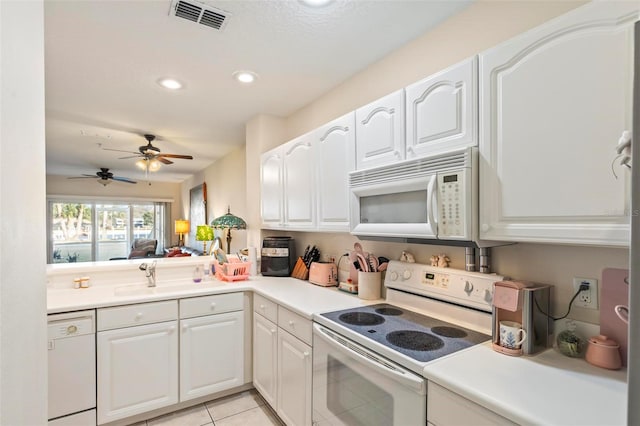 kitchen with light tile patterned flooring, sink, white cabinets, kitchen peninsula, and white appliances