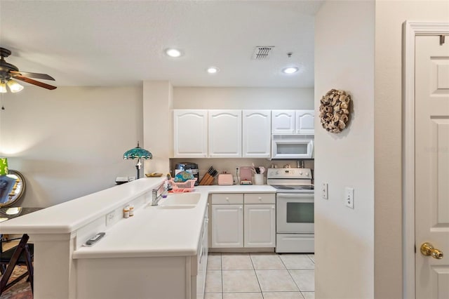 kitchen featuring sink, white appliances, kitchen peninsula, and white cabinets