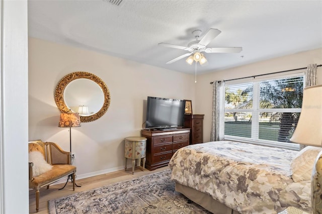 bedroom featuring a textured ceiling, ceiling fan, and light hardwood / wood-style flooring