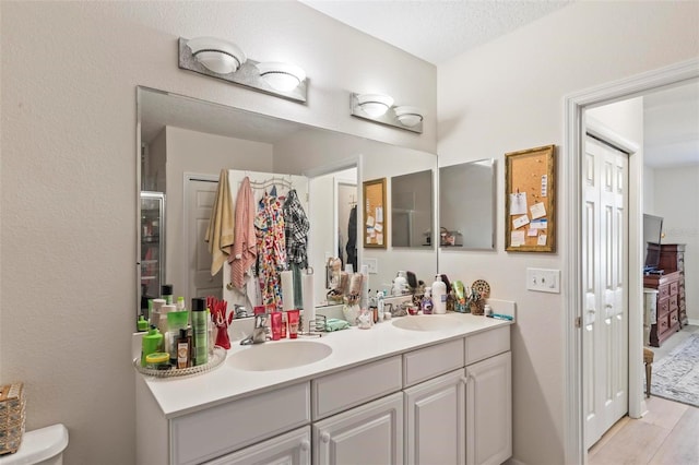 bathroom with vanity, toilet, hardwood / wood-style floors, and a textured ceiling