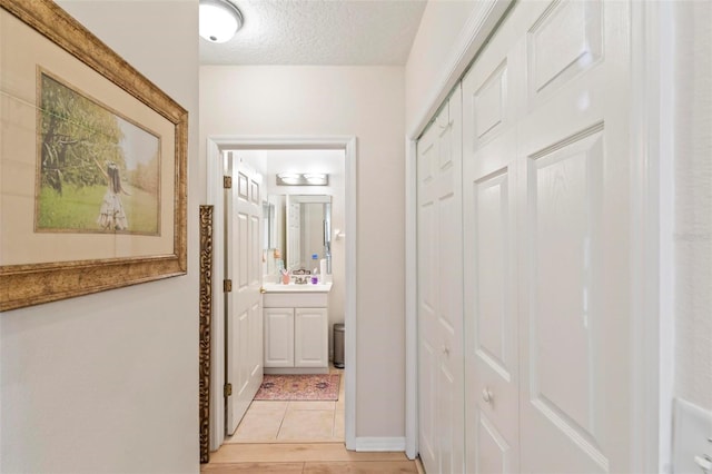 hallway featuring a textured ceiling and light tile patterned floors