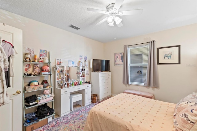 bedroom with ceiling fan and a textured ceiling