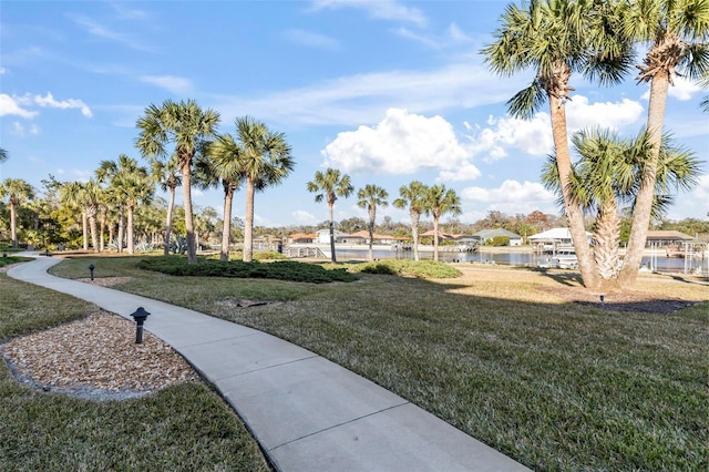 surrounding community featuring a water view and a lawn