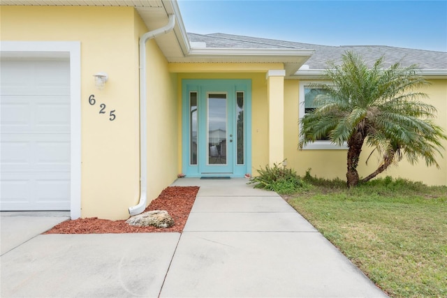 view of exterior entry featuring a garage and a lawn