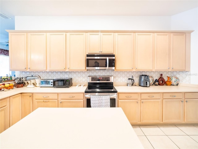 kitchen featuring backsplash, light tile patterned flooring, stainless steel appliances, and light brown cabinets