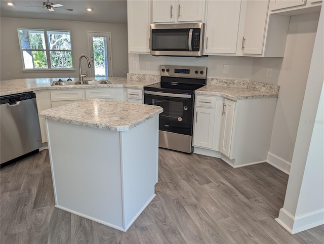 kitchen with sink, white cabinetry, a center island, appliances with stainless steel finishes, and light hardwood / wood-style floors