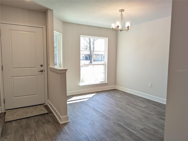 doorway to outside featuring a chandelier, a textured ceiling, and dark hardwood / wood-style flooring