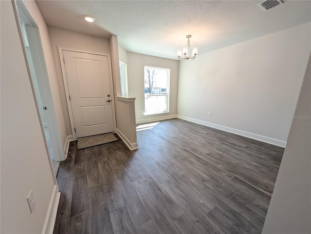 interior space featuring a textured ceiling, a notable chandelier, and dark hardwood / wood-style flooring