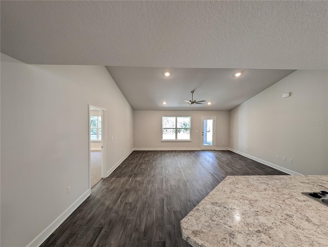 unfurnished living room with vaulted ceiling, dark hardwood / wood-style floors, a textured ceiling, and ceiling fan