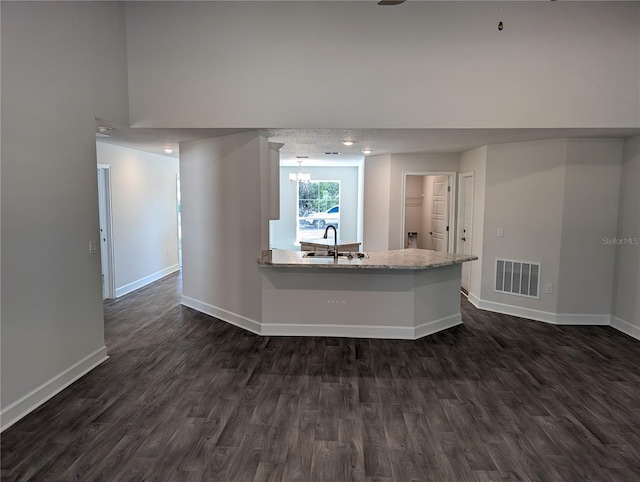 kitchen with dark hardwood / wood-style flooring, kitchen peninsula, sink, and a textured ceiling