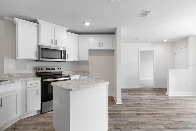 15 Serene Pl, Palm Coast, FL 32164 - kitchen with appliances with stainless steel finishes, white cabinetry, light countertops, light wood-style floors, and recessed lighting