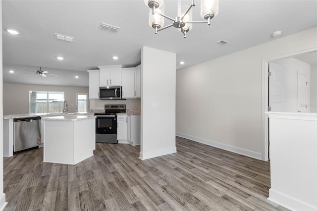 15 Serene Pl, Palm Coast, FL 32164 - kitchen with appliances with stainless steel finishes, a center island, light countertops, light wood-type flooring, and a chandelier