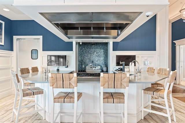 kitchen with tasteful backsplash, a decorative wall, a sink, and wood finished floors