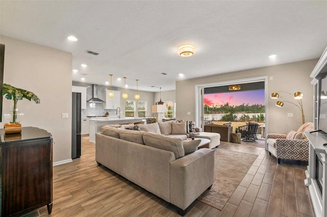 living room featuring visible vents, recessed lighting, light wood-type flooring, and baseboards