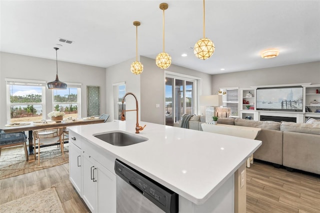 kitchen with dishwasher, visible vents, light wood finished floors, and a sink