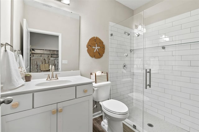 full bathroom featuring a shower stall, toilet, vanity, and wood finished floors