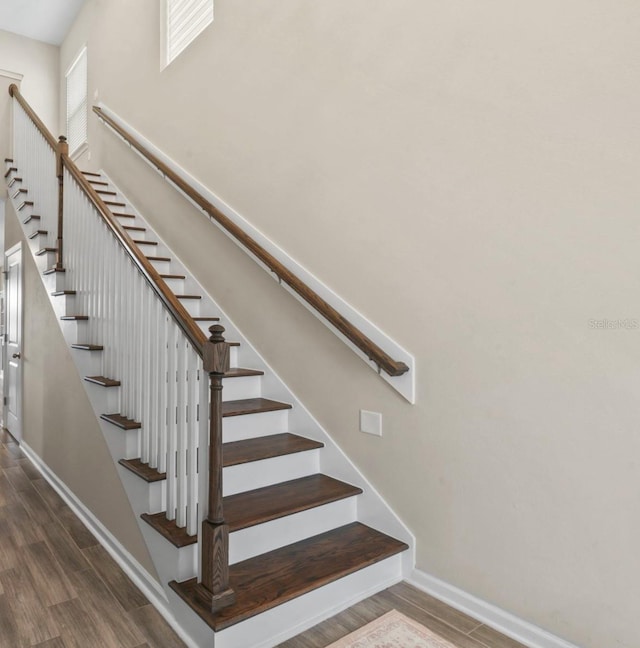 stairs with baseboards, a high ceiling, and wood finished floors