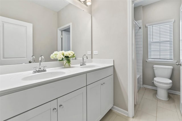 bathroom featuring a sink, baseboards, toilet, and double vanity