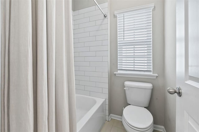 bathroom featuring toilet, baseboards, and shower / bath combo