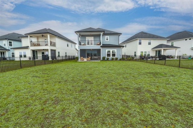 rear view of property with a fenced backyard, a lawn, a balcony, and ceiling fan