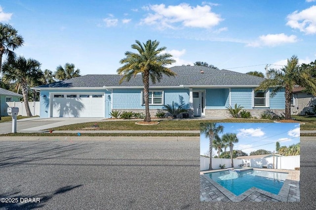 single story home with a garage, a pool with connected hot tub, fence, and concrete driveway