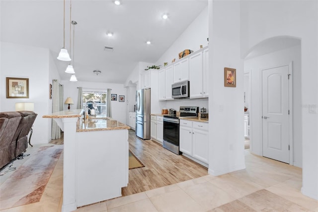 kitchen with appliances with stainless steel finishes, an island with sink, white cabinetry, a kitchen bar, and hanging light fixtures