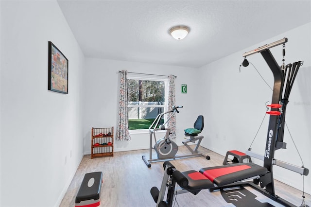 exercise area featuring wood-type flooring and a textured ceiling